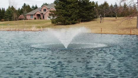 an aerated water fountain in the middle of a rural town pond