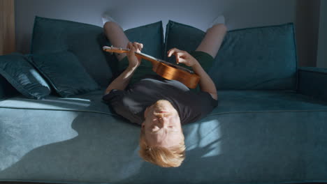 man playing ukulele on a couch