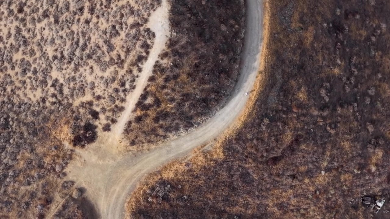 Aerial view looking down on a lone hiker traversing the hot rugged mountain trail in Southern California