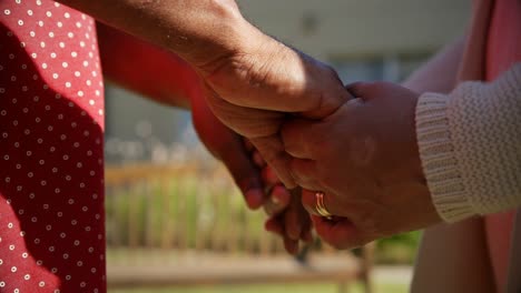 Mid-section-of-senior-couple-holding-hands-in-the-garden-of-nursing-home-4k