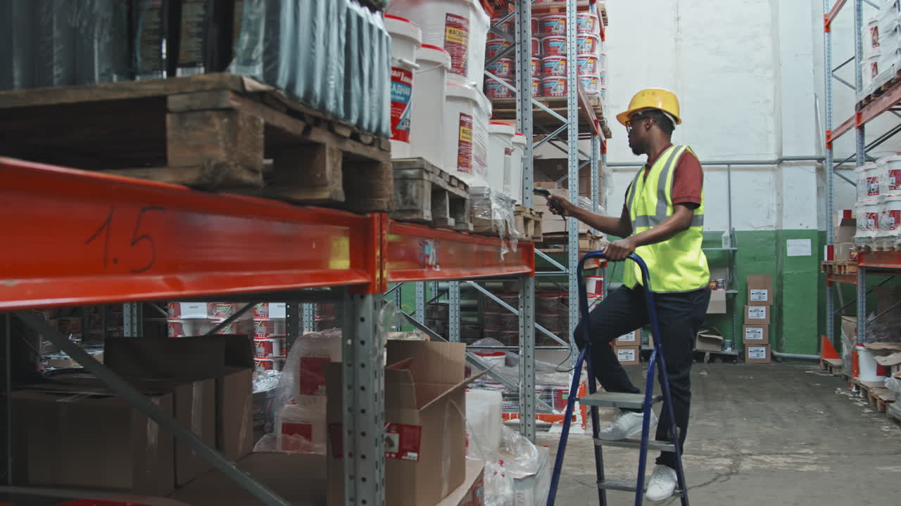 Male Worker in Hard Hat Scanning Boxes in Warehouse