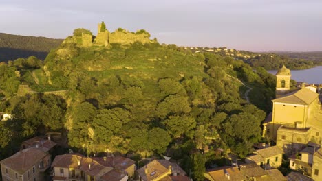 drone shot reveals orsinis fortress on lake bracciano at sunset