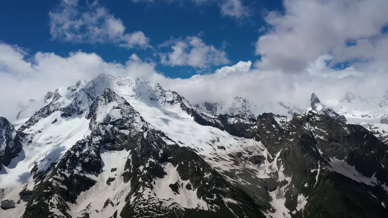vuelo aéreo a través de nubes montañosas sobre hermosos picos nevados de montañas y glaciares.