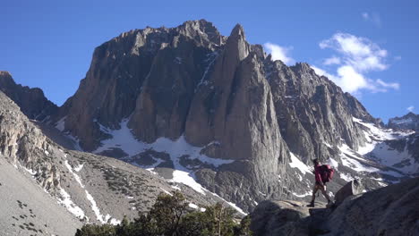 lonely female hiker on lookout in amazing sunny mountain landscape under summit with snow