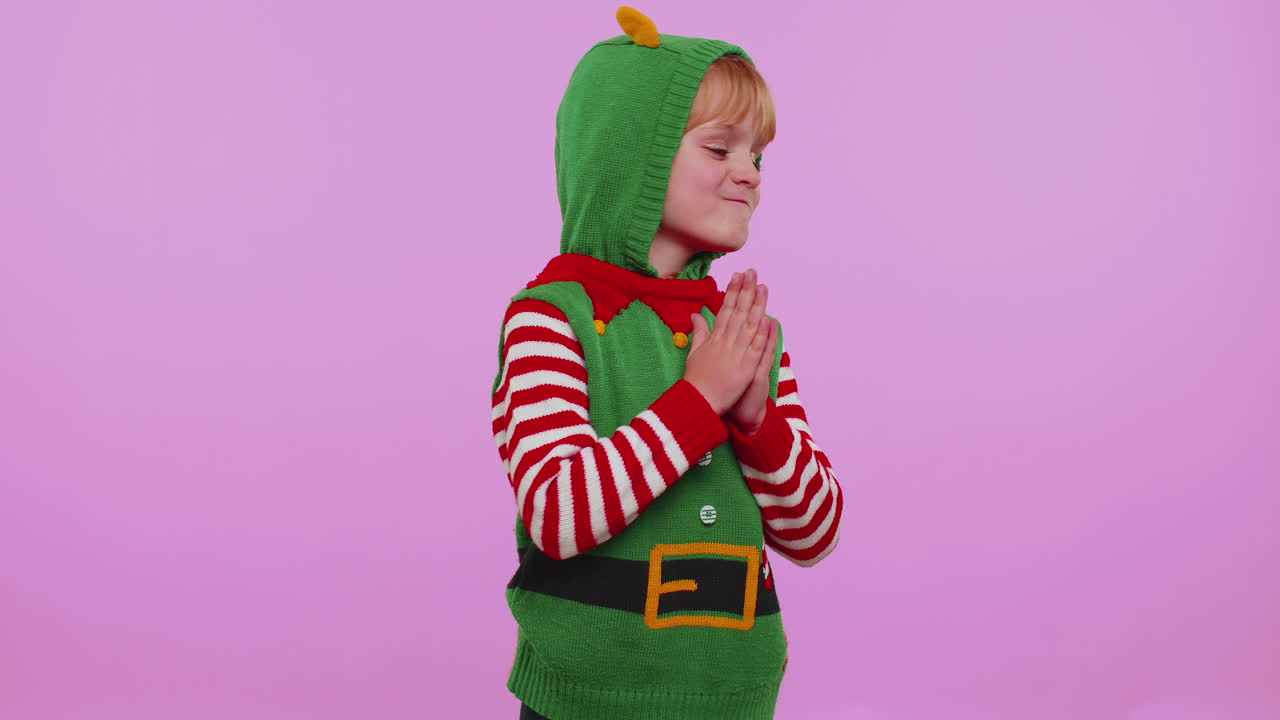 Veselá dívka v kostýmu Santy dostává vánoční dárek a projevuje úžas a radost.