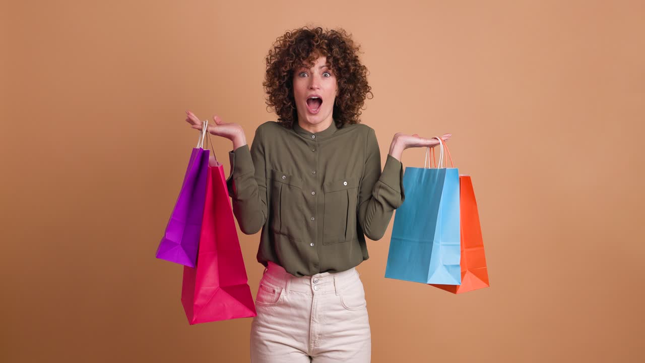 Happy woman with shopping paper bags in beige studio