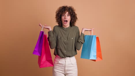 happy woman with shopping paper bags in beige studio