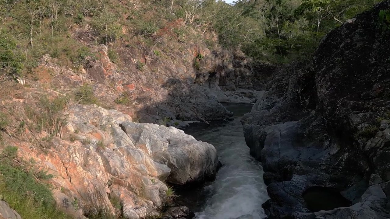 Rio São Miguel cortando um cânion de quartzito na Serra do Segredo, Chapada dos Veadeiros, Goiás, Brasil, com corredeiras turbulentas, formações rochosas erodidas e densa vegetação de Cerrado, filmagem em movimento baixo