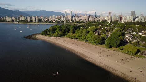 Personas-Que-Practican-El-Distanciamiento-Social-En-La-Playa-De-Kitsilano-Con-La-Playa-De-La-Bahía-Inglesa-Y-El-Horizonte-Del-Centro-De-Vancouver,-Columbia-Británica,-Canadá