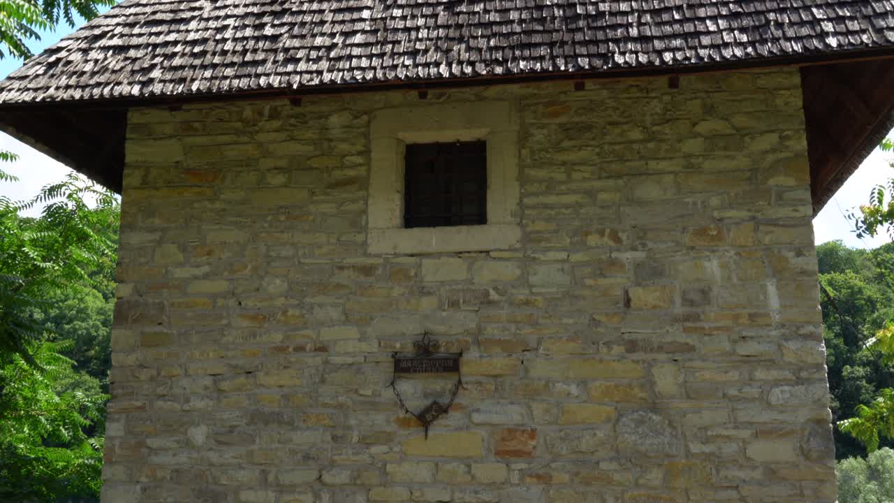Kushnirska Tower surrounded with greenery at Kamianets Podilski on a sunny day with white clouds blue skies. Tilt down.