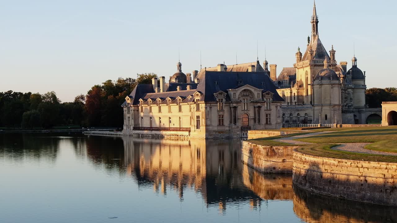 View of the Chateau de Chantilly castle surrounded by immense mirrors of water in Chantilly, Oise, France in daylight