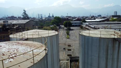 a medida que el dron se acerca, tres enormes tanques de agua oxidados aparecen a la vista, de pie como centinelas silenciosos en medio de la descomposición