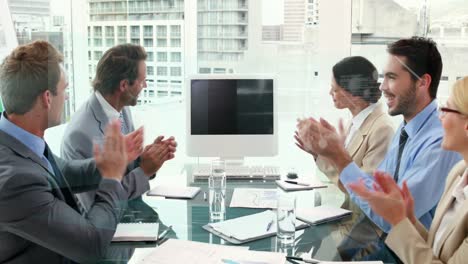 Animation-of-diverse-businesspeople-clapping-together-looking-at-a-computer-screen-with-copy-space