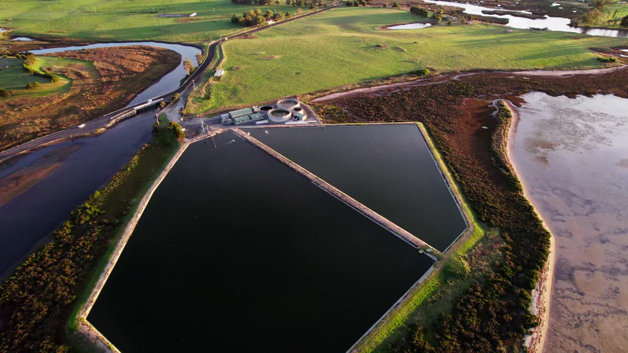 Aerial toward small sewage treatment plant near coastline, Tasmania