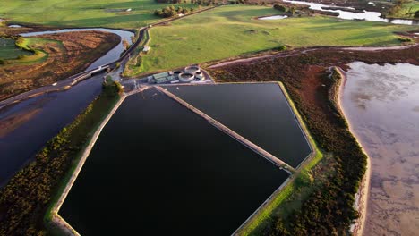 Aerial-toward-small-sewage-treatment-plant-near-coastline,-Tasmania