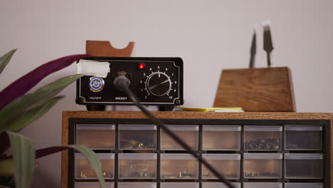 man turns on and tunes electrical leather edger in workshop