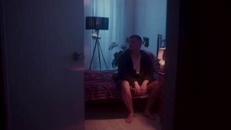 man sitting alone in a dark bedroom
