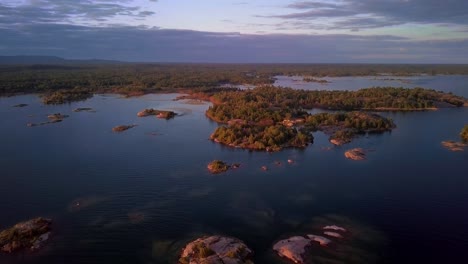 islas rocosas de granito con pinos verdes en un lago azul claro al atardecer, muñeca aérea de drones en