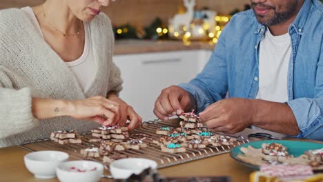 multi ethnicity couple packing gingerbread cookies as small christmas gifts.