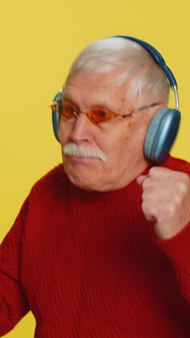 anciano sénior elegante escuchando música a través de auriculares y bailando abuelo jubilado feliz