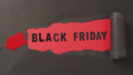 Ripped-black-paper-with-black-friday-sale-text-in-black-on-red-background