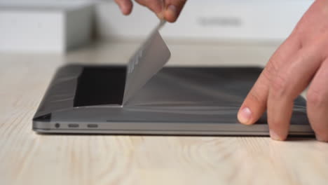 Close-up of peeling the protective plastic from a brand new laptop