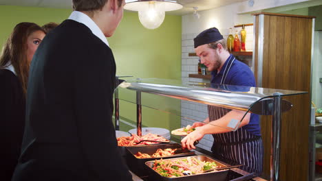 Teenage-Students-Being-Served-Meal-In-School-Canteen