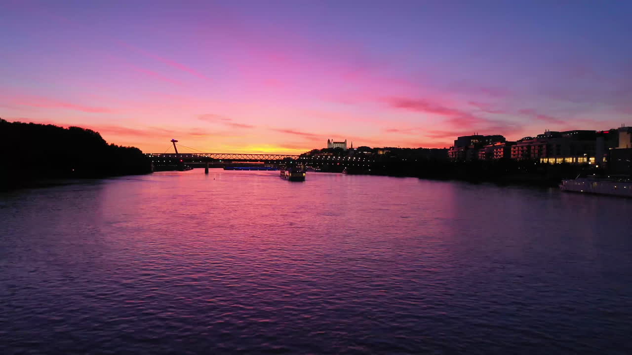 Scenic panoramic footage of a sunset in the city of Bratislava with unusual colors caused by volcano eruption. Flying with a drone low over the  river Danube. Mesmerising gradient.