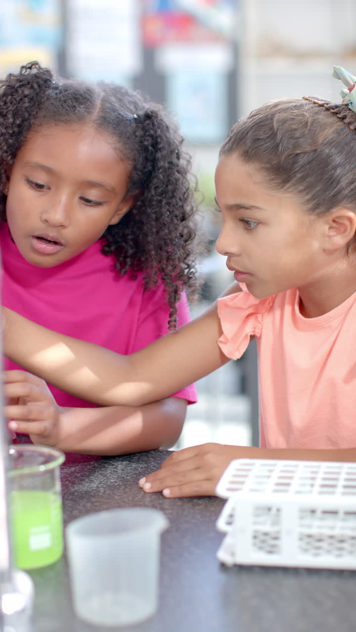 Vertical video: In school, two young girls are focusing on science experiment