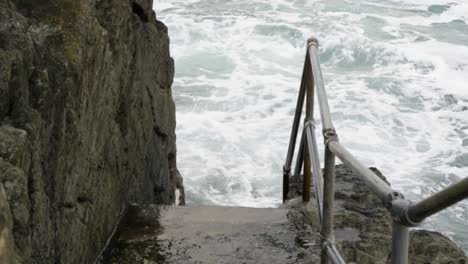 tidal waves hit on the concrete staircase at newquay harbour in cornwall, united kingdom