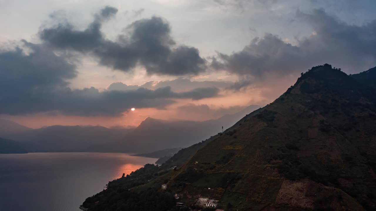 hiperlapso aéreo de drones con una hermosa puesta de sol detrás de las montañas en el lago de atitlán, guatemala