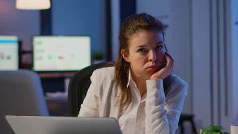 Businesswoman-looking-tired-in-camera-sighing-resting-head-in-palm