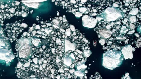 boat sailing through melting sea ice floats in alaska, usa