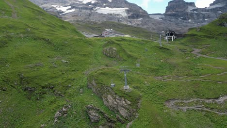 Amplia-Vista-De-Drones-De-Una-Instalación-De-Teleférico-En-Los-Alpes-Suizos,-Prados-Y-Montañas-Rocosas,-Obwalden,-Engelberg