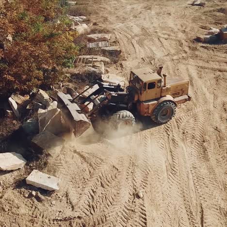 professional bulldozer with a bucket is spreading sand near the stones on the background of the quarry. close-up
