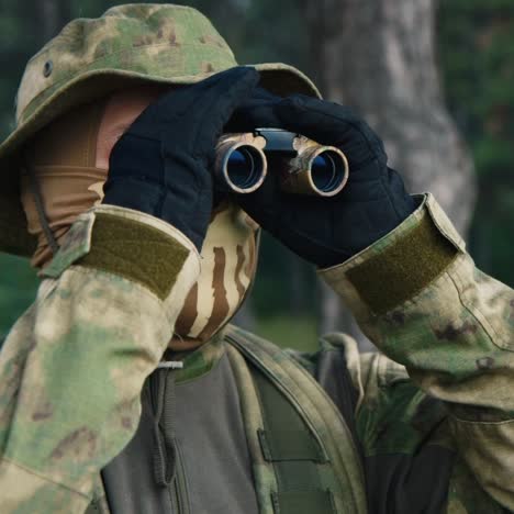 a soldier looks through binoculars