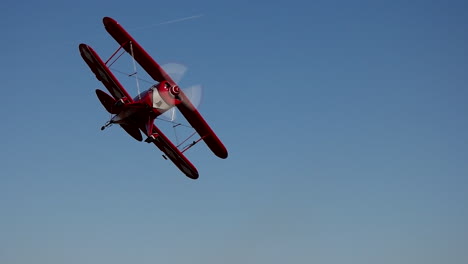 aerobatic pitts s2b biplane performs a turn away from the camera during a low pass