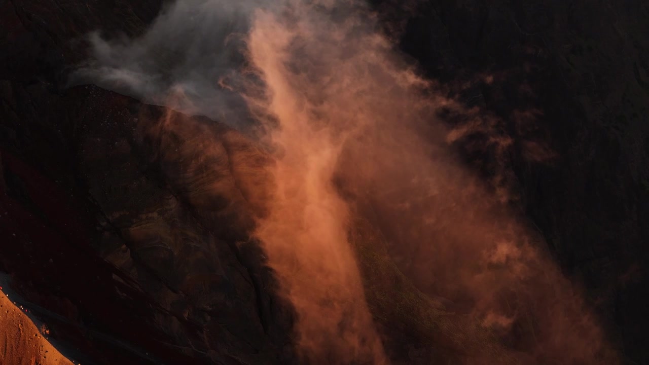 En æterisk sky stiger op ved siden af Mount Rinjani vulkanske højderyg, der gløder i varmt solopgangslys, luftfotooversigt over lette, drømmende teksturer