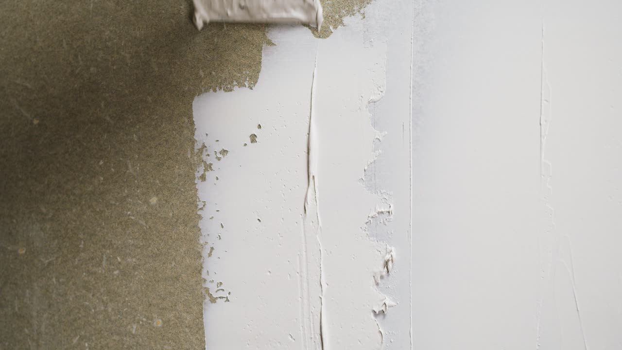Close-up van een hand die een muur bepleistert met een spatel