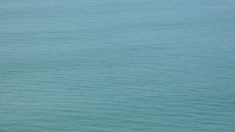 lone kayaker paddles on calm ocean near harbor entrance - lyttelton harbor, new zealand