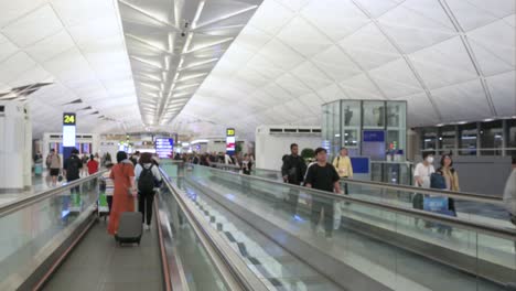 busy airport terminal with passengers on moving walkways