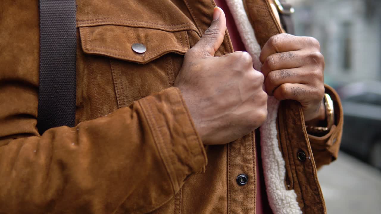 Black man with shoulder backpack stands outdoor near the office center