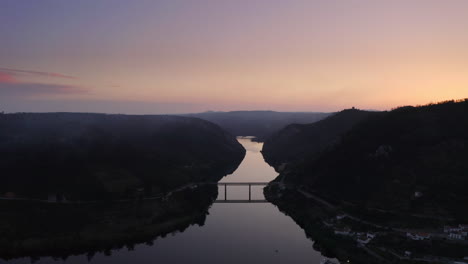 Hermoso-Puente-Reflejo-En-El-Río,-Entre-Montañas-De-Silueta