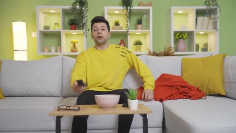 Funny-clumsy-teenager-is-dismantling-adjustable-table-while-watching-tv-at-home.-Unfortunate-young-man.