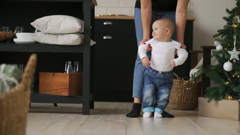 baby taking first steps with mother help