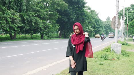 a fashionable afghan woman in hijab with black t shirt stands confidently on the street in a crowded city