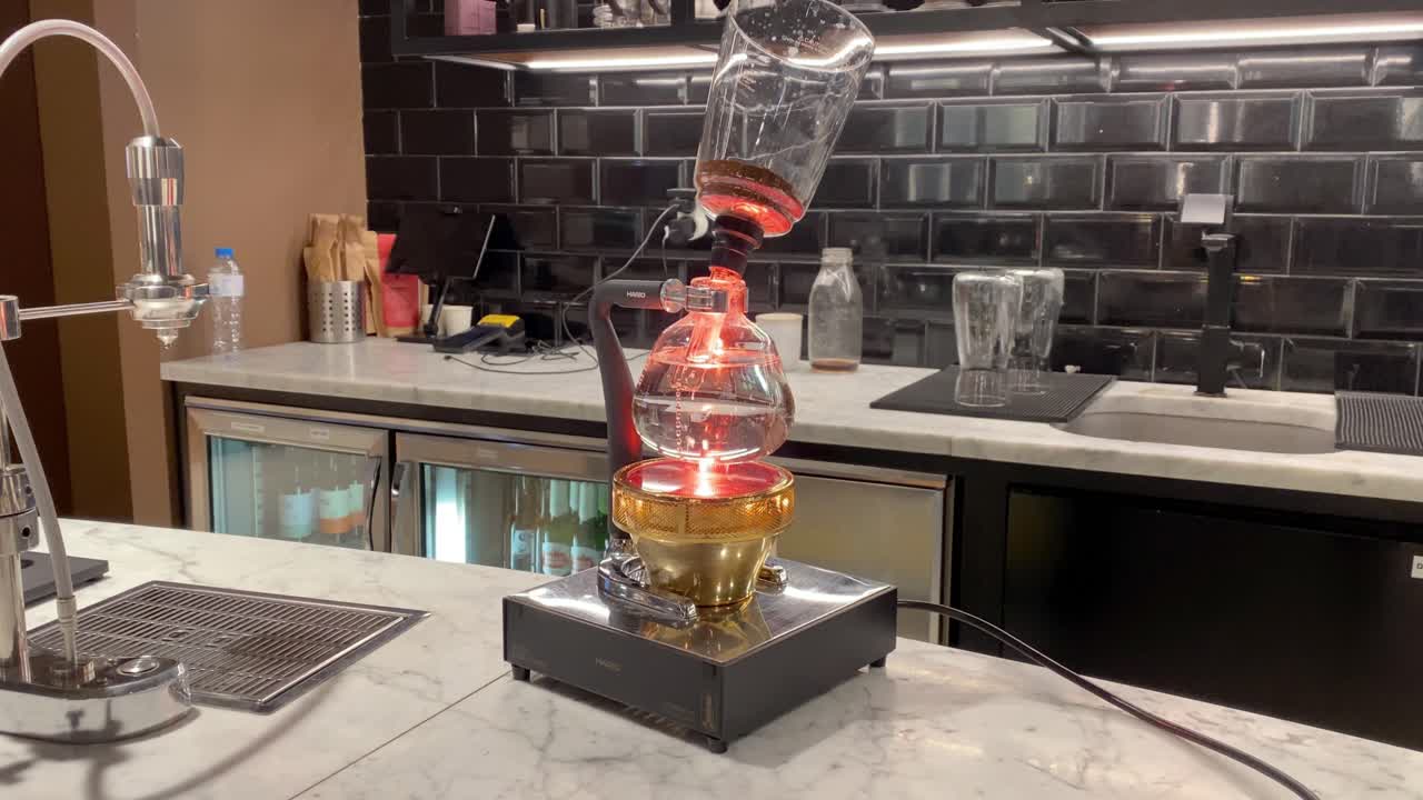 강한 커피를 끓이는 과정에서 진공 커피 메이커의 시야를 닫습니다:물이 끓고 별도의 플라스크에 커피를 붓는다