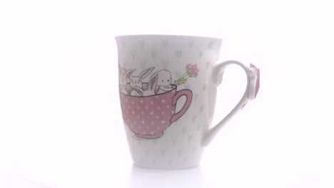 taza de té con ilustracion conejitos sobre fondo blanco en estudio fotográfico