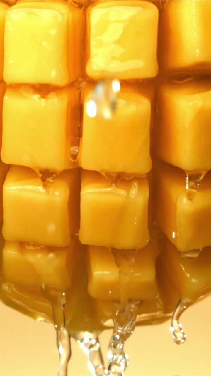 Acqua che gocciola su cubetti di frutta gialla al rallentatore