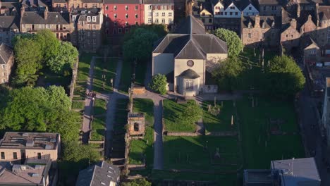drone orbit captures the historic canongate kirk and nearby dunbar’s close, revealing edinburgh’s rich heritage and charming architecture in soft light